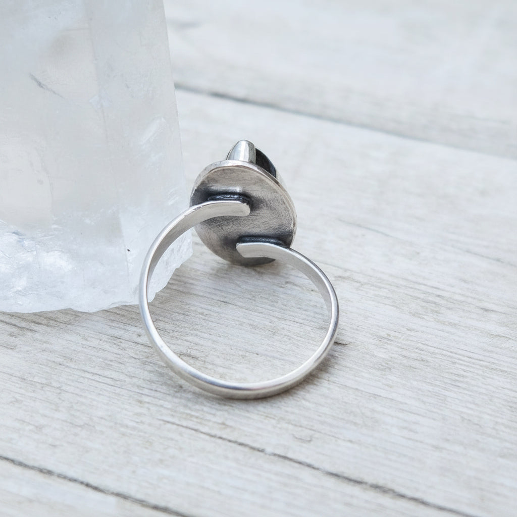 Silver ring with a unique design on a wooden surface